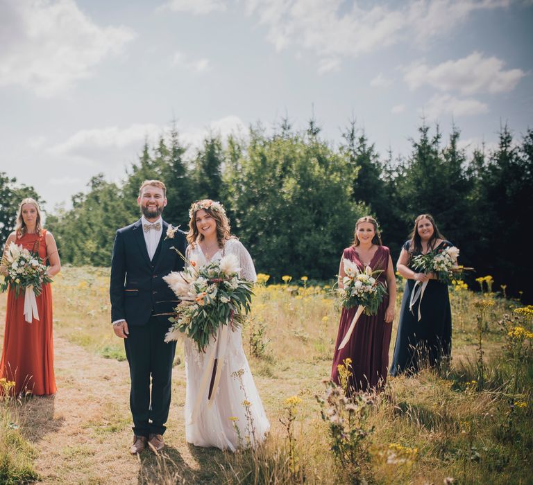 Bride & groom stand in field surrounded by their wedding party