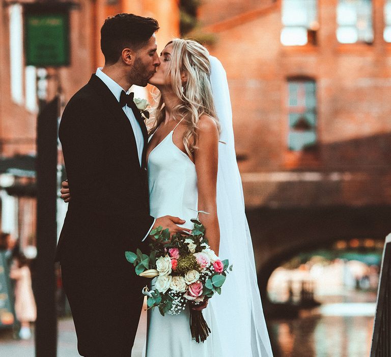 Bride and groom kissing by the canal in Birmingham at intimate Gas Street church wedding