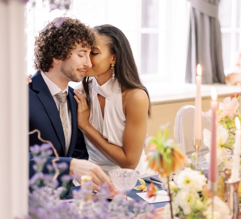 Bride leans in to kiss groom as she holds her hand to his shoulder