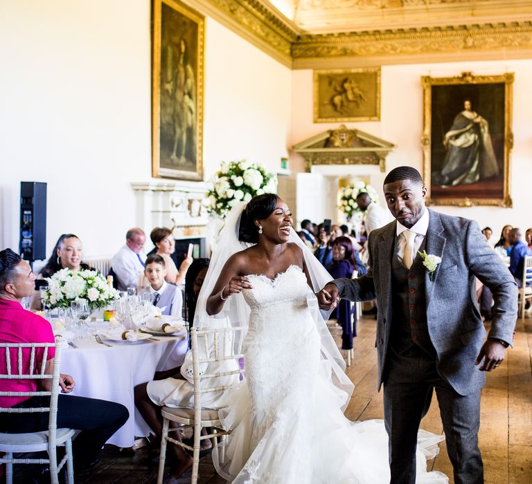 Bride & groom walk together in reception room on their wedding day