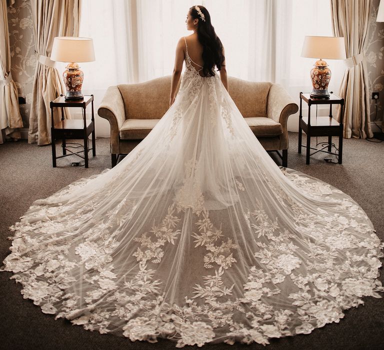 Bride portrait from behind at bay window with wedding dress train fanned out