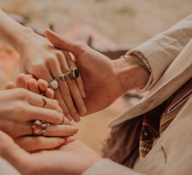 Bride & groom hold hands as bride wears silver chunky rings with bright stones 