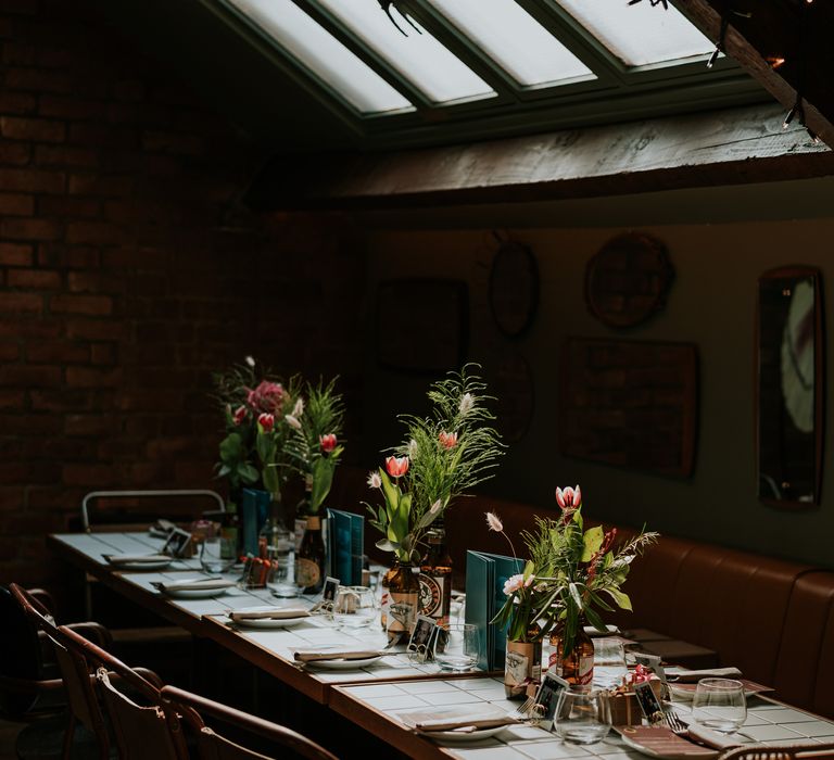 Horticulture wedding reception featuring bottles filled with florals and sky light 