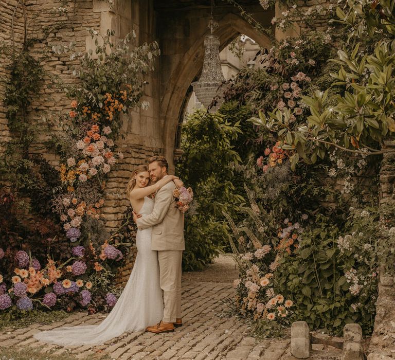 Bride and groom portrait at Euridge Manor under the castle arch with chandelier and pastel coloured flowers 