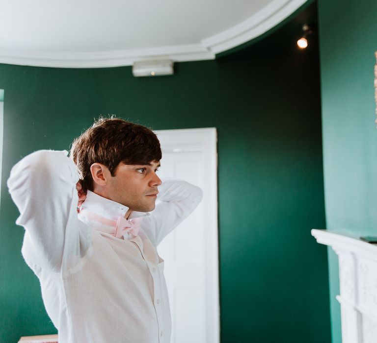 Groom looks in the mirror on the morning of his wedding