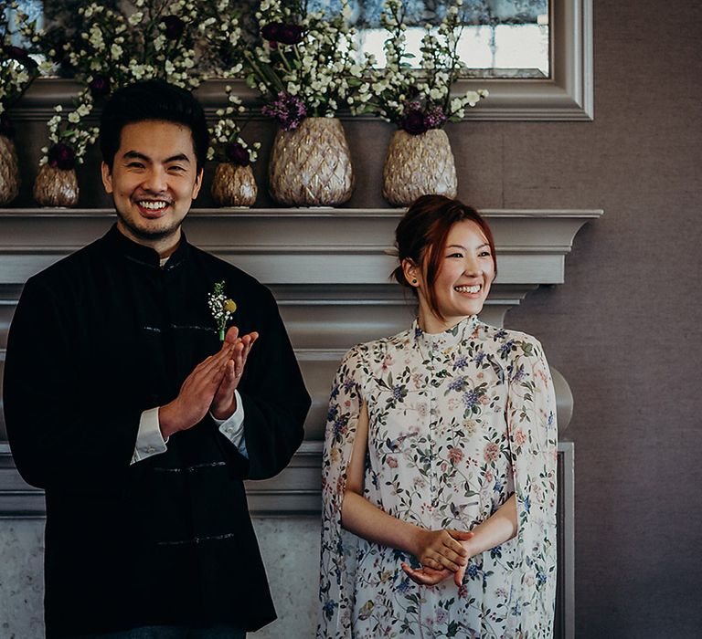 Intimate wedding at Old Marylebone Town Hall with Easy Asian groom in a navy Jacket and bride in a floral short dress with cape sleeves