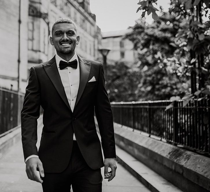 Stylish groom in a black tuxedo and bow tie 