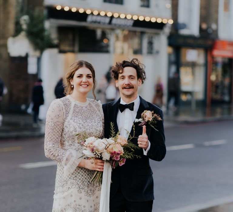 Bride & groom stand with one another in the street after wedding ceremony as bride holds her floral bouquet