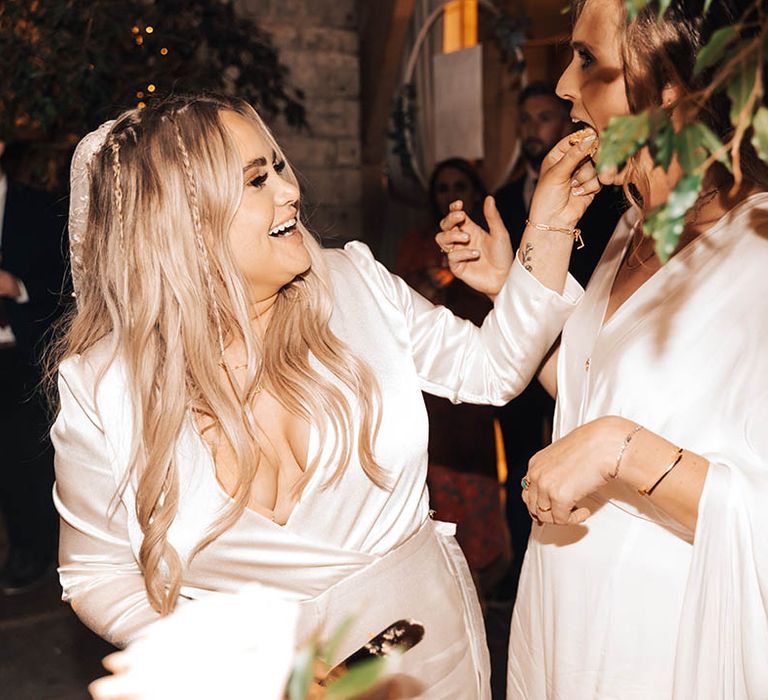 Bride feeds cake to her wife on their wedding day