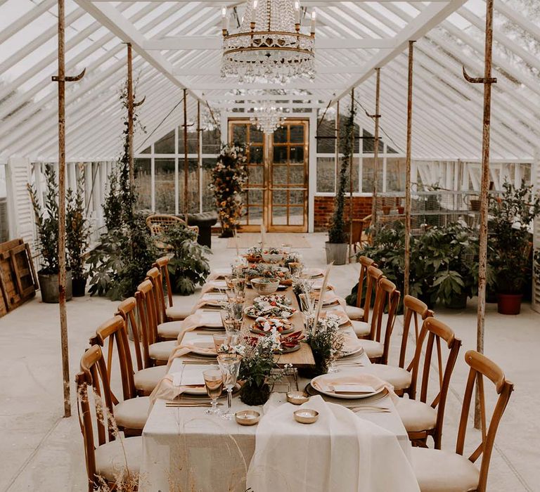 Glass house wedding reception with wedding food placed in the centre doubling up as table decor 