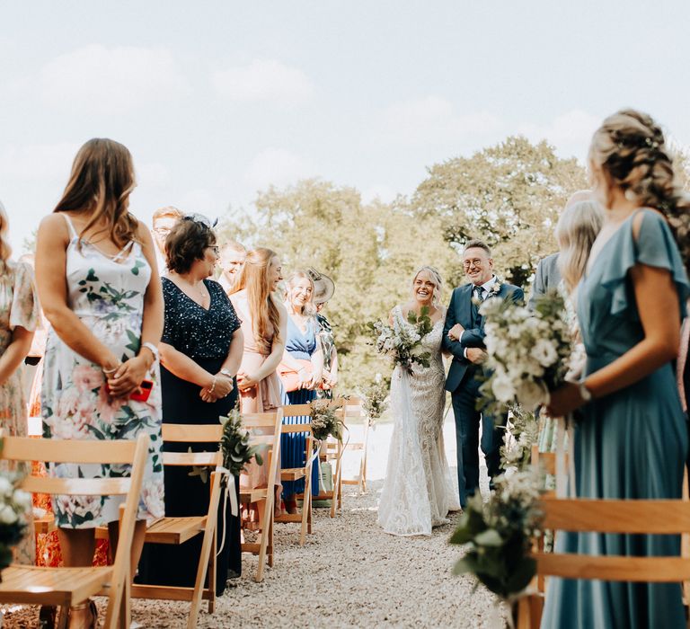 Bride walks down the aisle at outdoor wedding ceremony