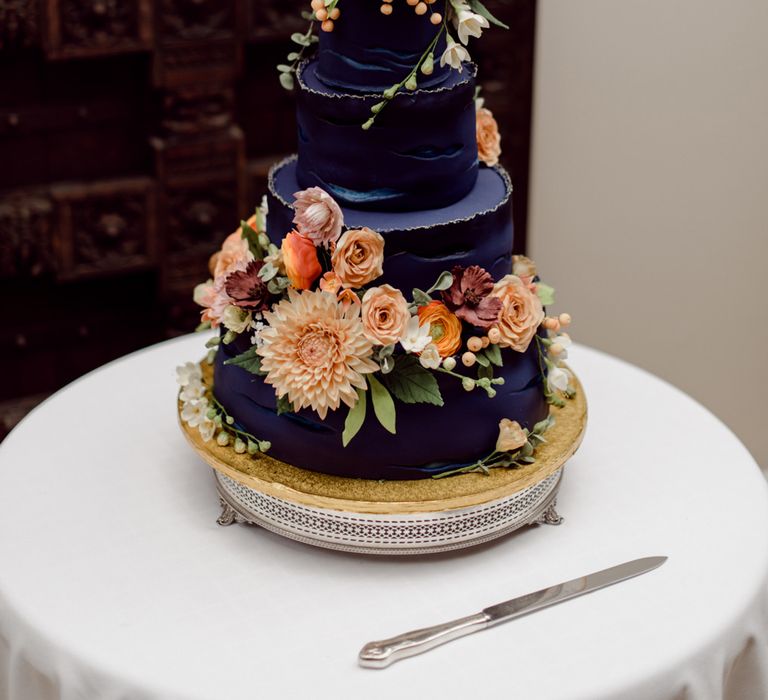 navy wedding cake with orange flower decor and cake topper 