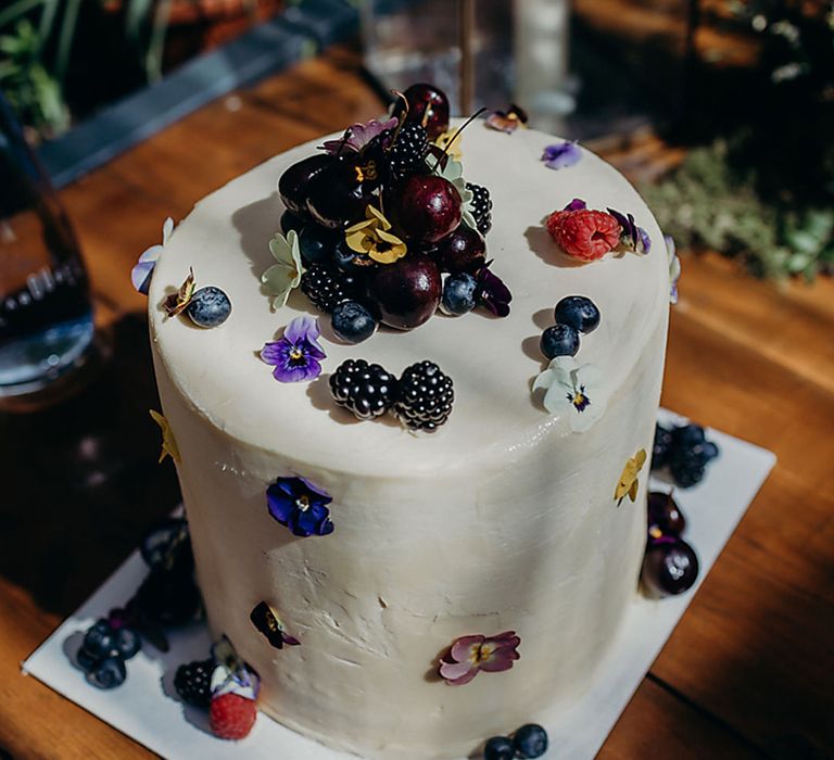 single tier iced wedding cake decorated with cherries and berries 