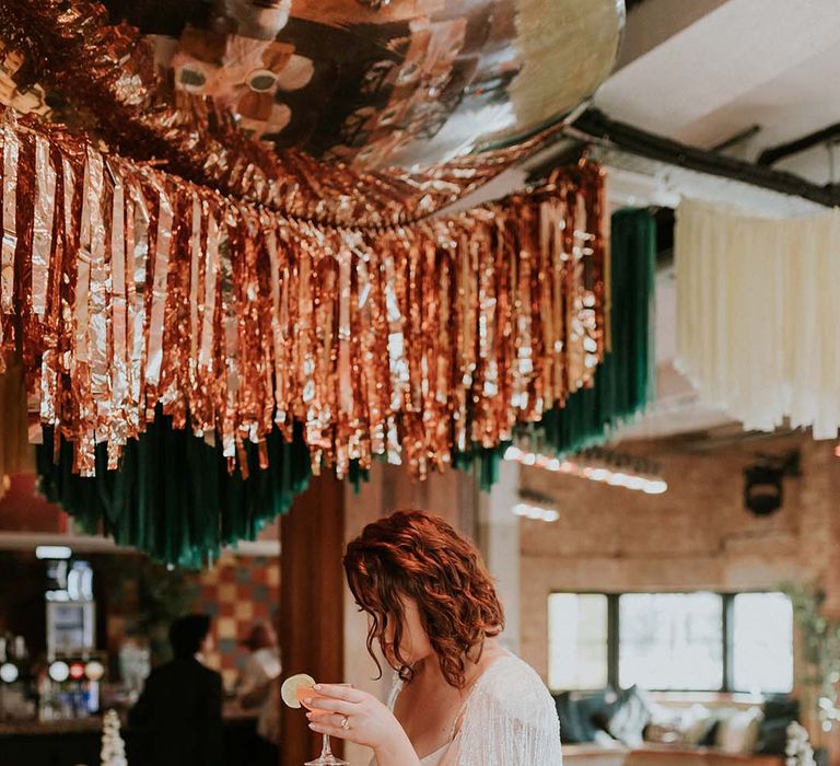 Bride holds cocktail during wedding reception