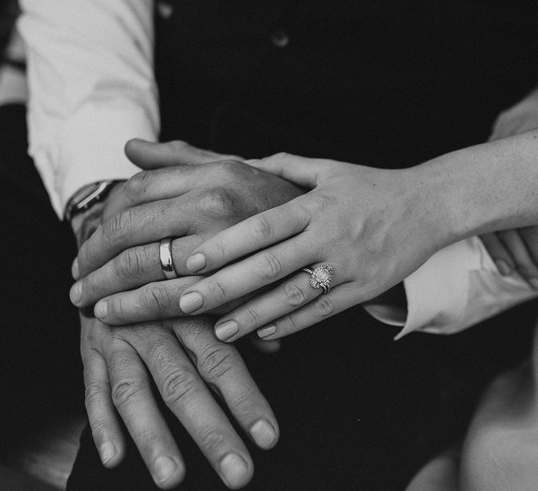 Bride and groom holding hands showing off their wedding and engagement rings 