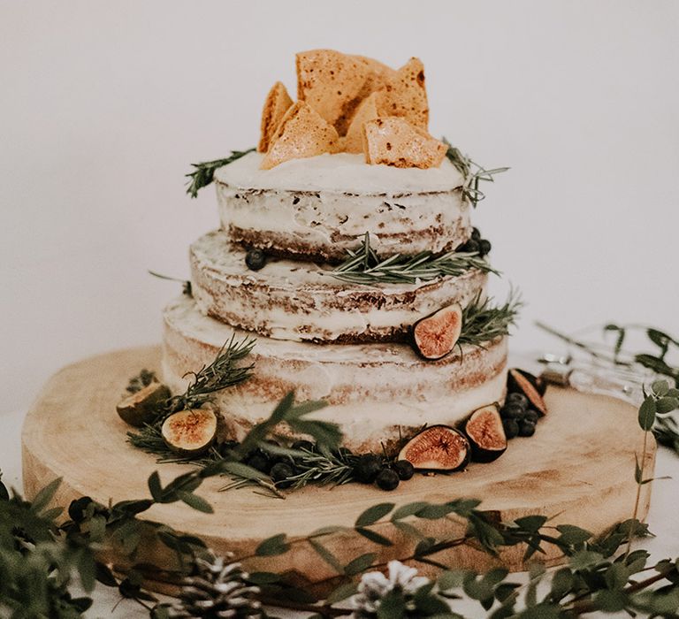 Rustic wedding cake complete with naked frosting, honeycomb decor and florals surrounding on a wooden block