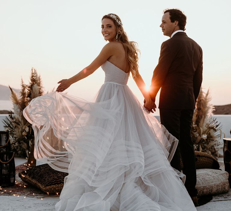 Bride & groom walk together during the sunset 