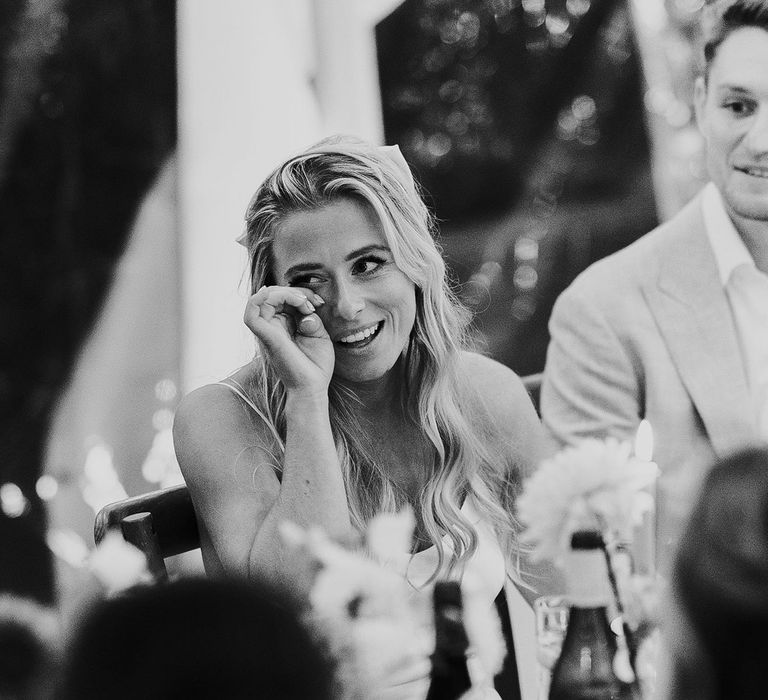 Emotional bride wipes her eyes during wedding speech at marquee wedding reception