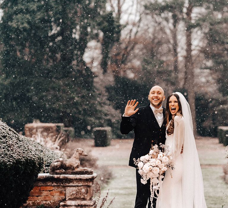 Snowy winter wedding at Iscoyd Park with real bride Jessamy Stoddart in a long sleeve wedding dress and cathedral length veil and her groom Ryan in a three-piece black suit 