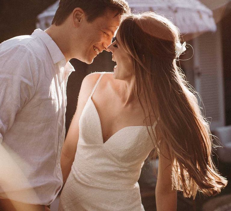 Bride in fitted v-neck lace wedding dress with long brown hair in half up half down style with groom in white shirt 