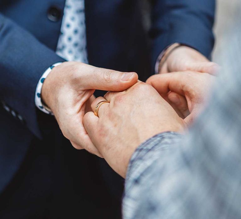 Grooms hold hands on their wedding day