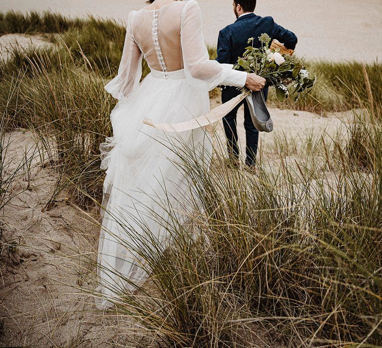 Bride and groom walk down onto the beach during their wedding day at Cornwall 