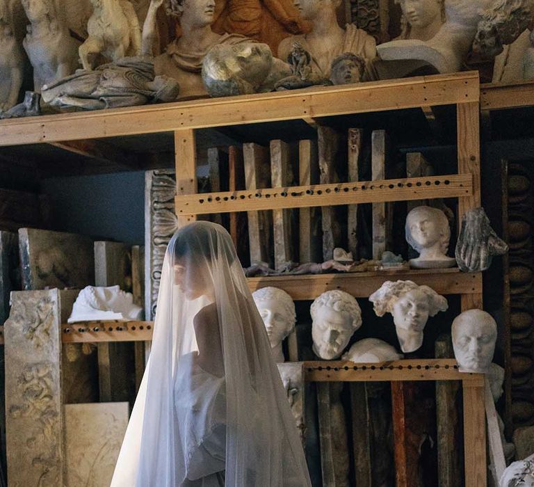 Bride sits wearing long veil covering her whole head and body