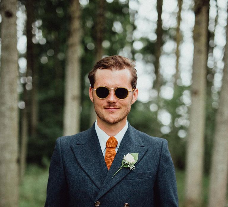 Rustic French destination wedding with groom in a navy double breasted suit, orange tie and sunglasses 