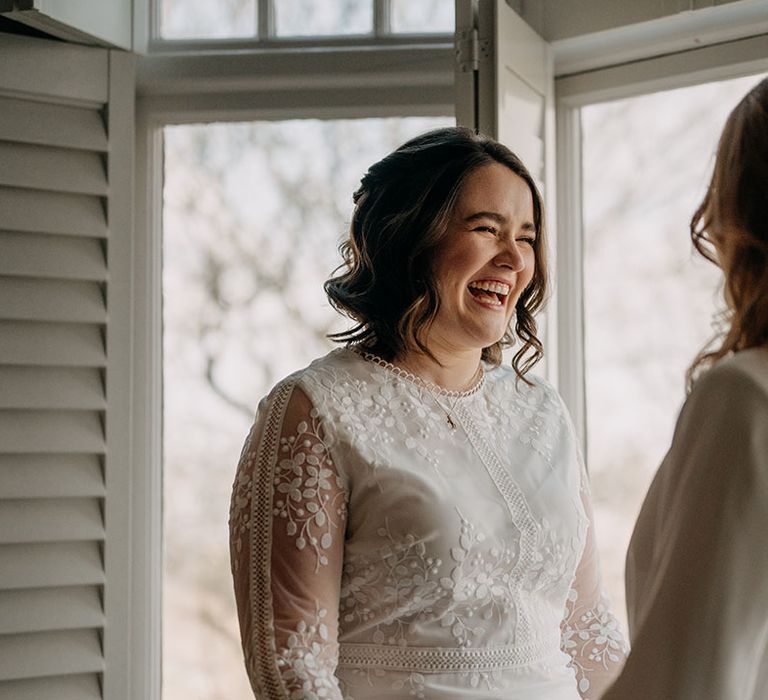 Bride looks lovingly at her wife on her wedding day whilst wearing boho gown from Coast 