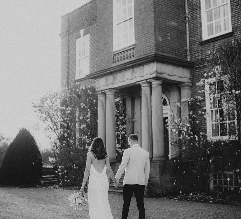 Bride and groom walk hand in hand for their romantic intimate wedding at Iscoyd Park venue 