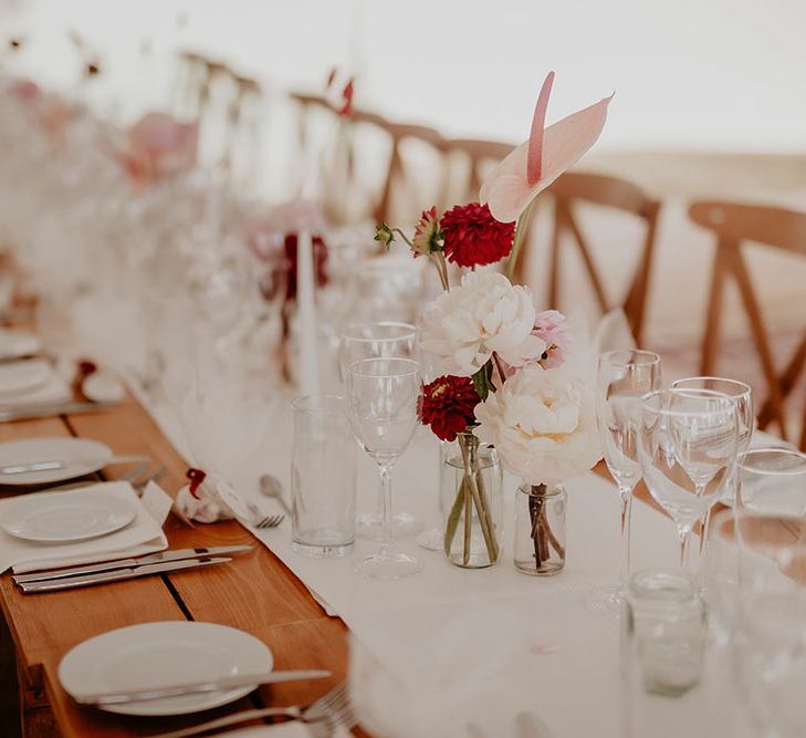 Wooden banquet tables with white table runner and white and pink wedding flowers 