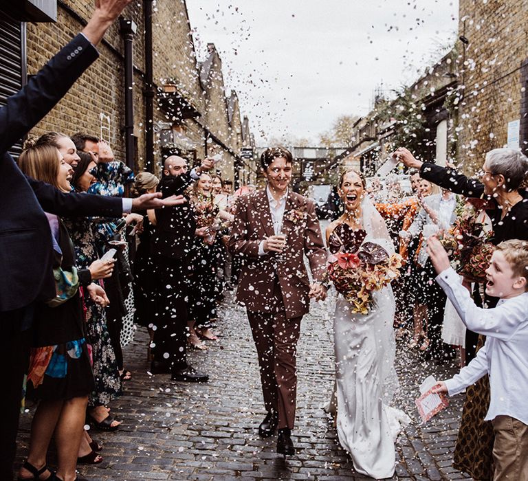 Wedding guests throw white confetti over the happy couple 