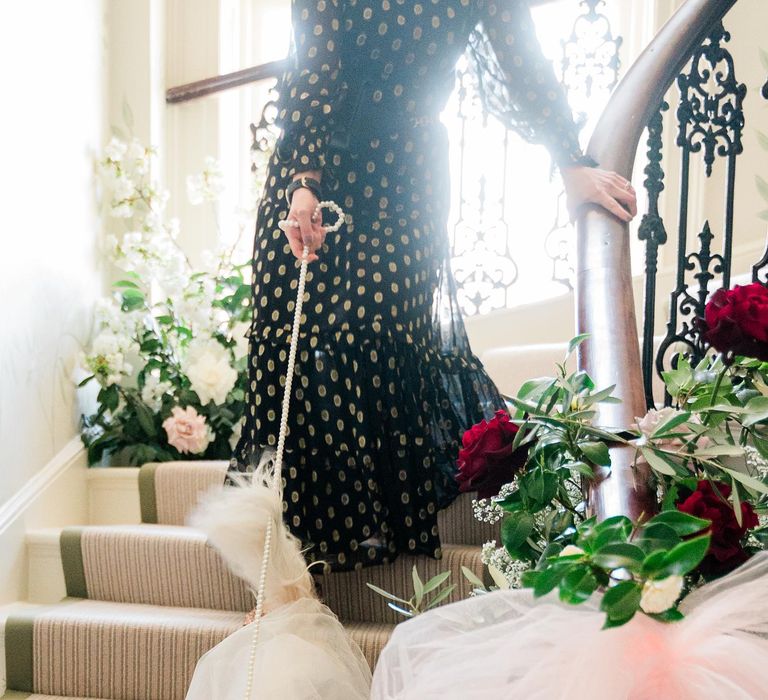 Dog ring bearer walks down staircase wearing veil matching the bride 