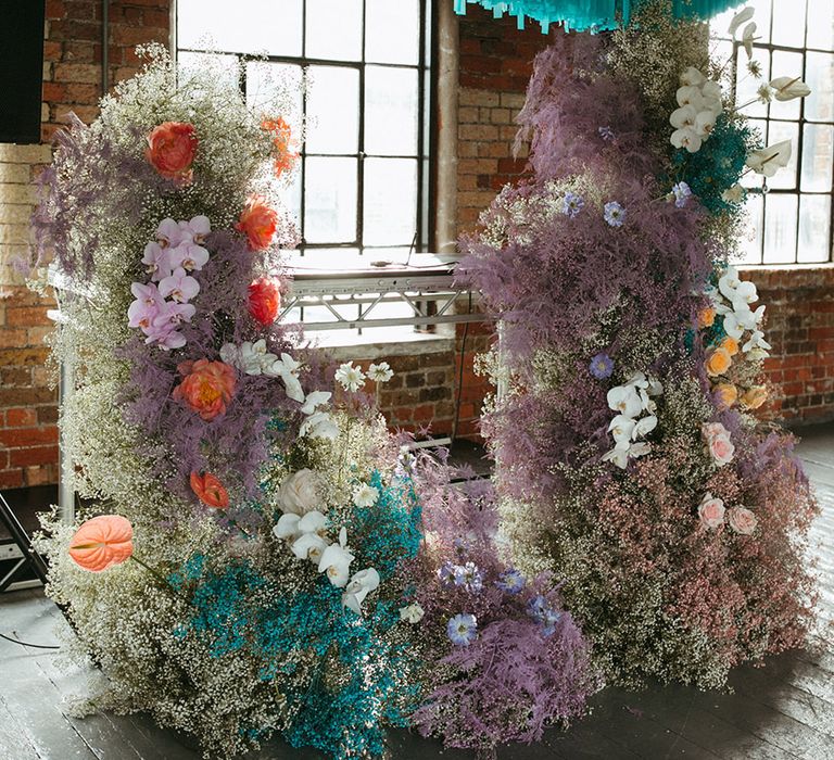 Blue wedding streamer decor with coloured gypsophila flowers in columns for the DJ area