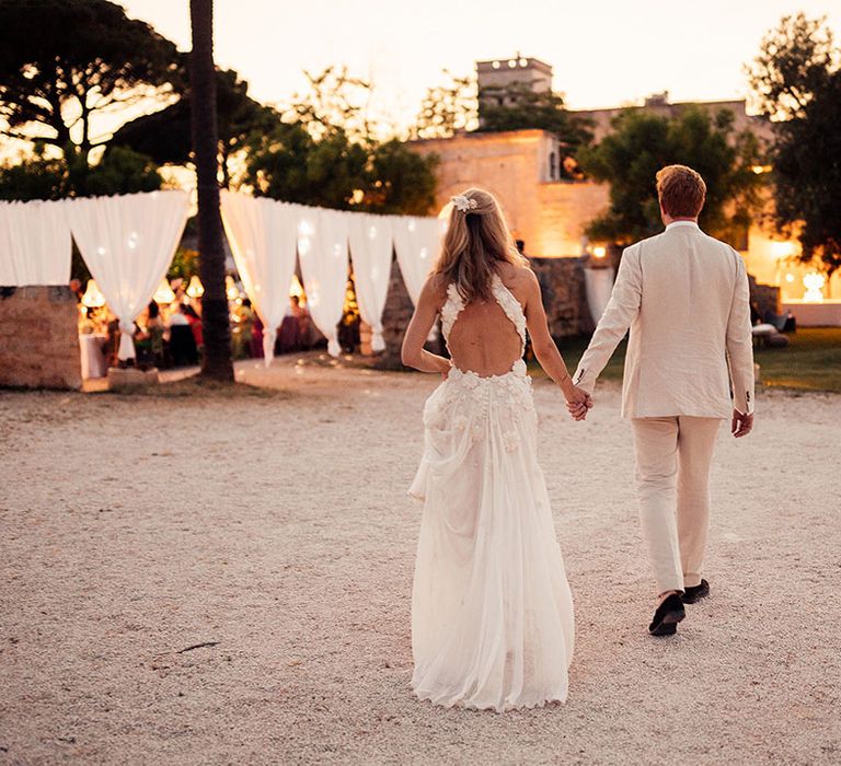 Bride in a flower Emma Beaumont wedding dress walking with the groom at their destination wedding 