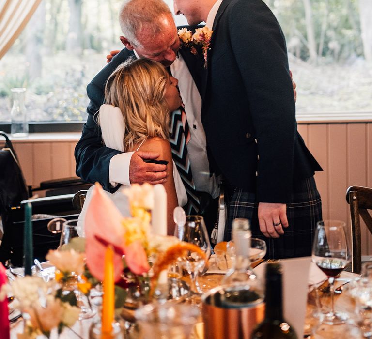 Bride & groom hug wedding guest during reception 