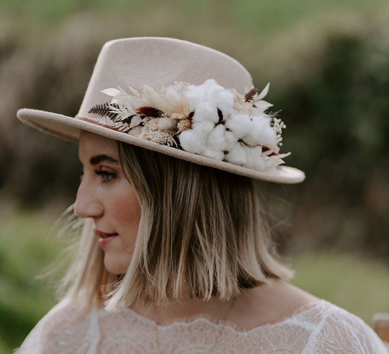 Bride wearing a beige hat decorated with cotton and dried flowers 