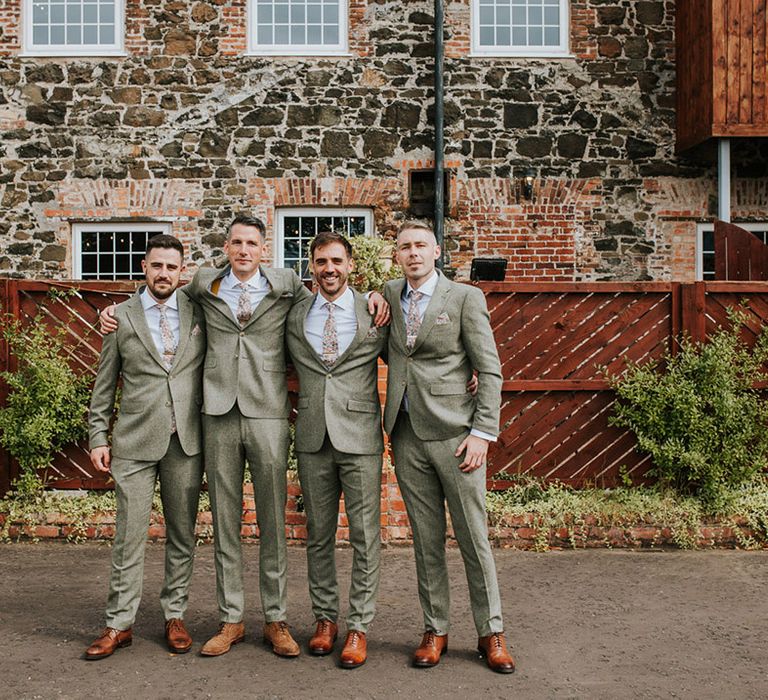 Groom and groomsmen posing together in matching suits with floral ties for the wedding in Northern Ireland 