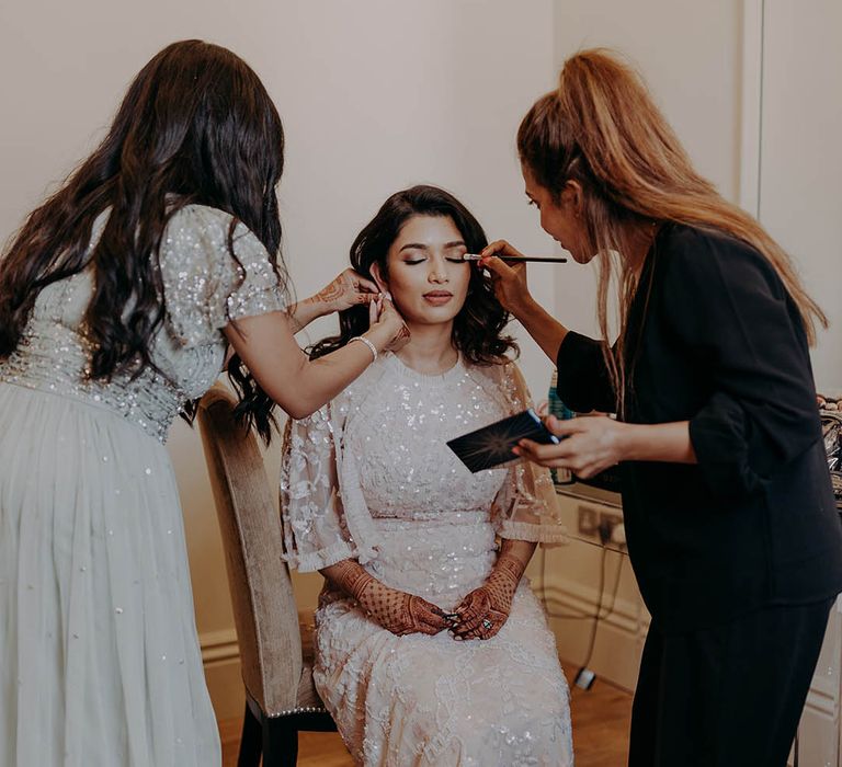 South East Asian bride has her makeup done before wedding reception whilst wearing Needle & Thread dress