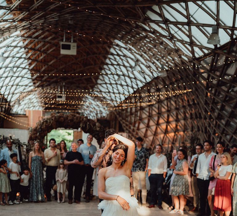 Wedding museum wedding venue with the bride and groom sharing their first dance together with the bride in a strapless ruffle dress and groom in summer pink shirt