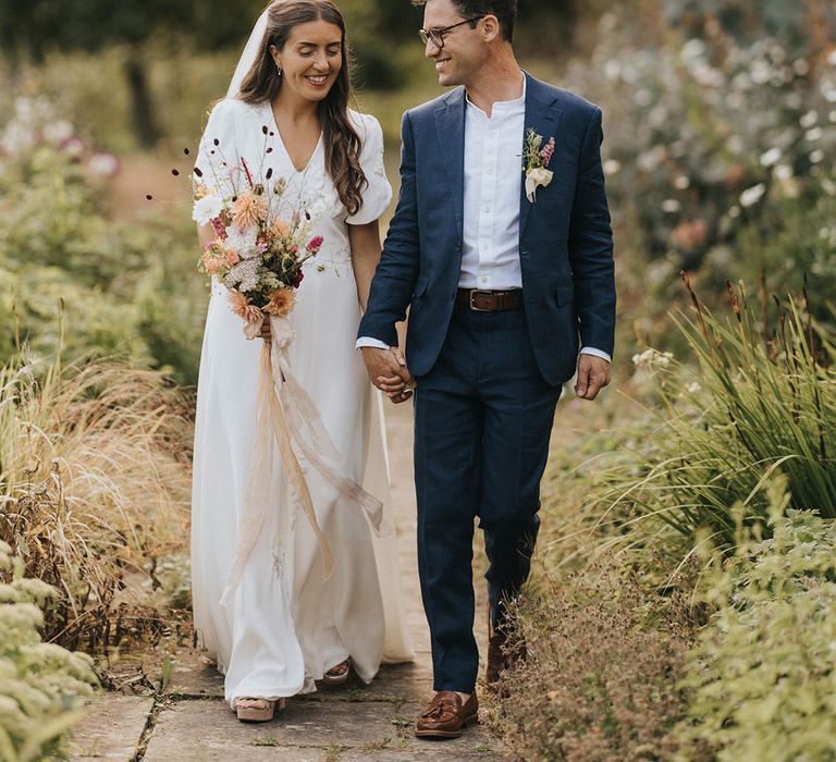 Bride in short sleeve embroidered wedding dress with veil holding rustic wedding flower bouquet 