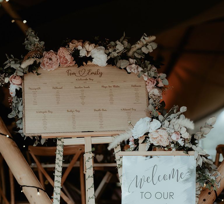 Rustic wedding decor complete with wooden seating chart and wildflower decor 