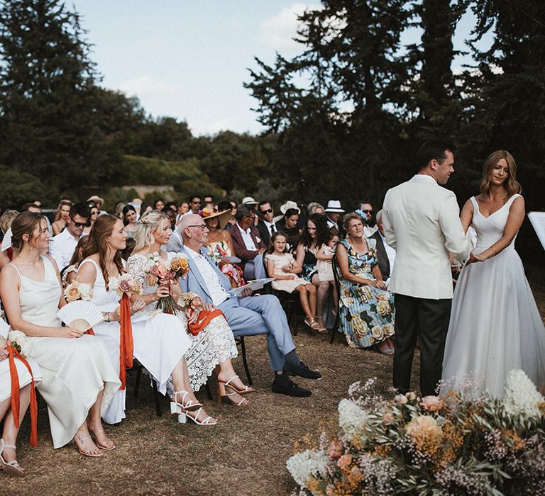 Wedding guests look on during outdoor wedding ceremony in Tuscany 