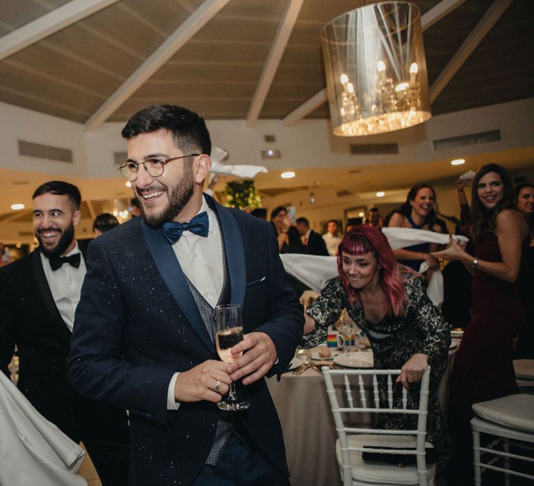 Groom in a navy blue tuxedo with speckles on and a bow tie