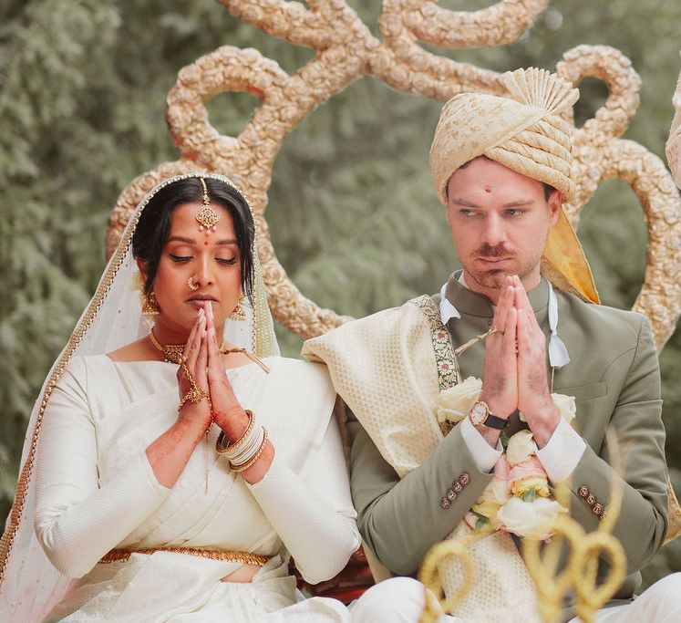 Bride in a cream Lehenga and groom in a green and gold Sherwani at Hindu wedding ceremony 