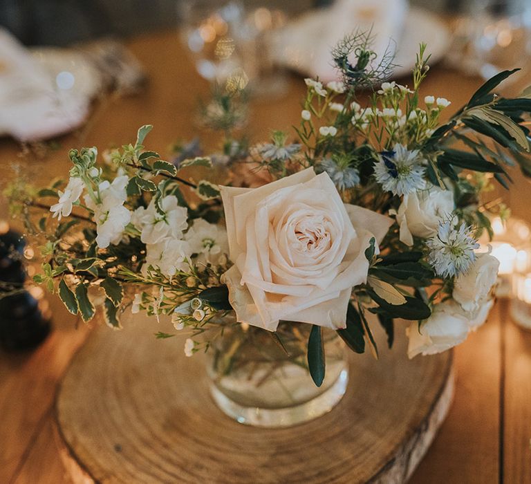 wedding centrepiece decor with pink rose and thistle flower stems in bottles on tree slices 