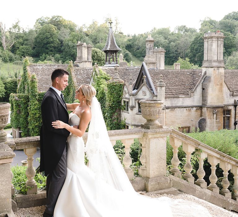 Bride in fitted mermaid Pronovias wedding dress with the groom in morning suit for wedding at The Manor House, Castle Combe wedding venue 