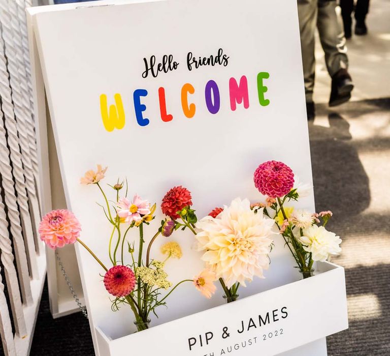 Simple white wedding welcome sign with colourful lettering and bright flowers including dahlias and cafe au lait dahlia 