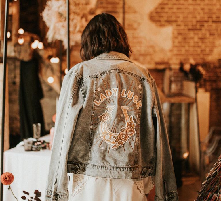 Bride in light wash wedding denim jacket with horse shoe badge and 'Lady Luck' 