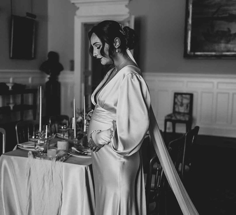 pregnant bride in a satin wedding dress with long sleeves 